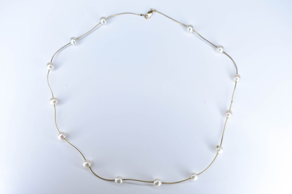 14K Gold & Stationed Pearl Necklace 11.33 grams.: 14K yellow gold snake link with 14 approx. 12mm natural pearls, 20.25" total length, 11.33 grams.