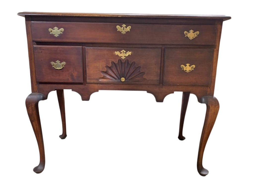 Mahogany Queen Anne Lowboy Circa 1830: Mahogany lowboy featuring drawers with brass hardware, including a central drawer with a fan-shaped carving. The piece rests on cabriole legs. The top surface shows some wear (see photos)