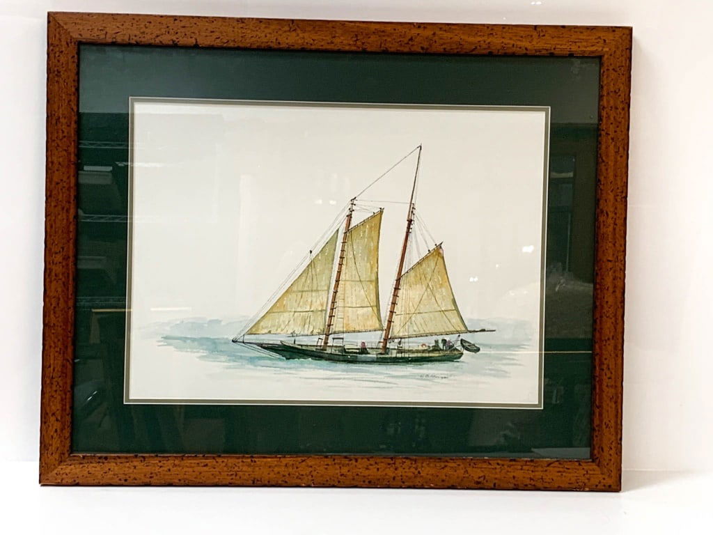 Watercolor by H.B. Milligan: Watercolor painting by artist H.B. Milligan depicting a sailboat with two sails at sea. Features a double mat in green and white and is framed in a speckled wood frame with glass glazing. Artist's sig