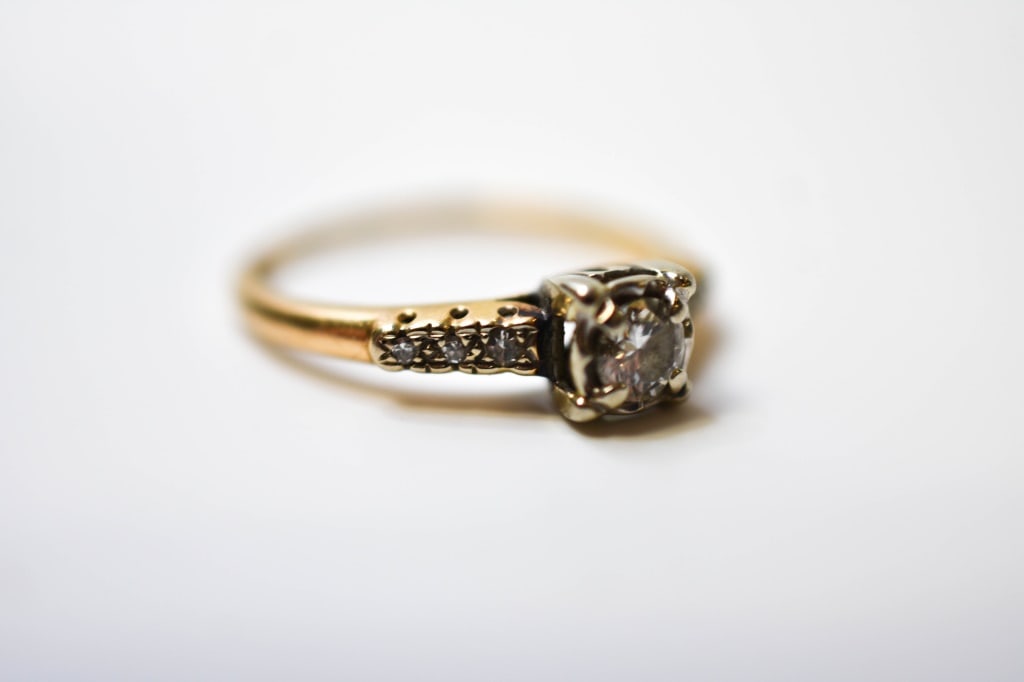 14K Yellow Gold & Diamond Engagement Ring 2.08 Gr: A timeless 14K yellow gold engagement ring featuring a sparkling round brilliant-cut diamond set in a secure four-prong setting. The center stone is complemented by a series of round accent diamonds p
