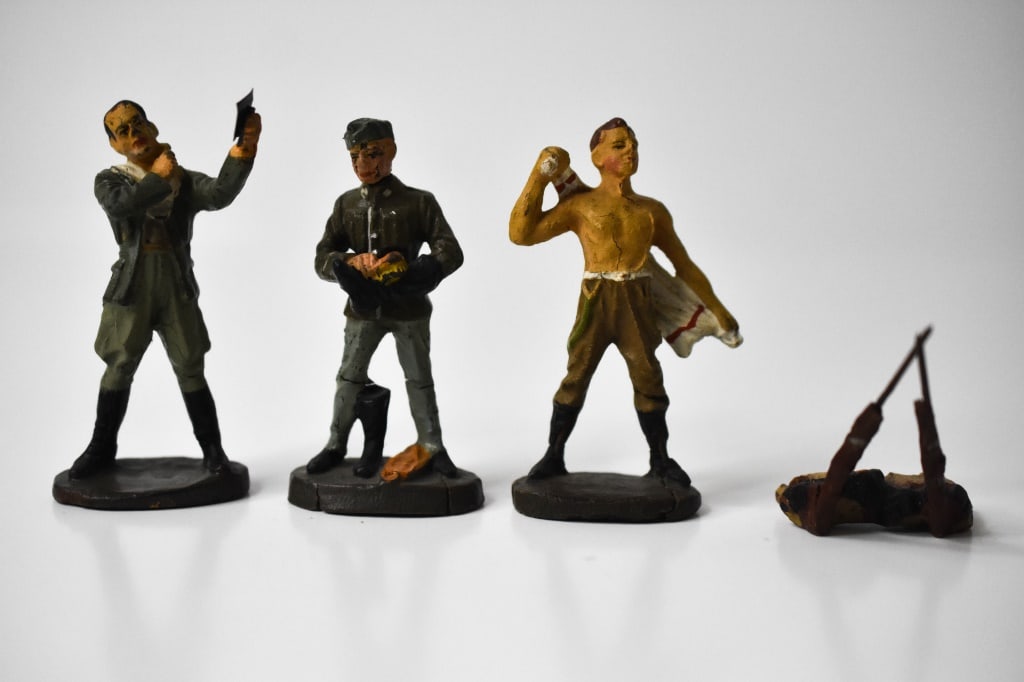 Elastolin Composition Soldiers Cleaning Up: Roughly 3 inches tall. Polishing boots, shaving and drying his back. 4th piece is 2 rifles and 2 backpacks. Shoe polisher looks like his head was reattached. They have typical age cracks ad paint loss