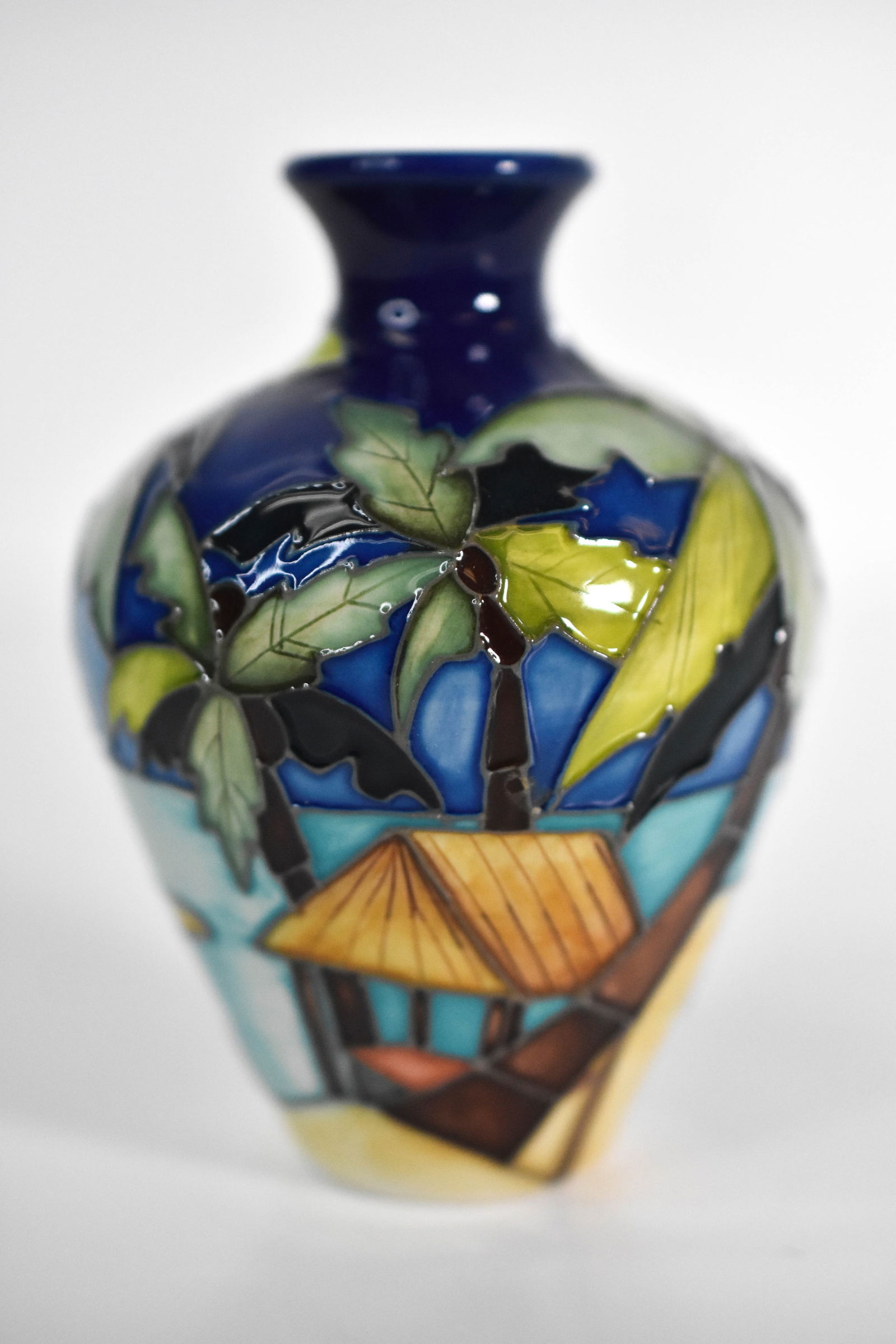 Moorcroft “Tropical Island?? Vase by Emma Bossons: "A charming and rare Moorcroft pottery vase designed by Emma Bossons, featuring a tropical island scene with palm trees, a coastal hut, and gentle ocean waves. The vibrant glaze captures Bossons’