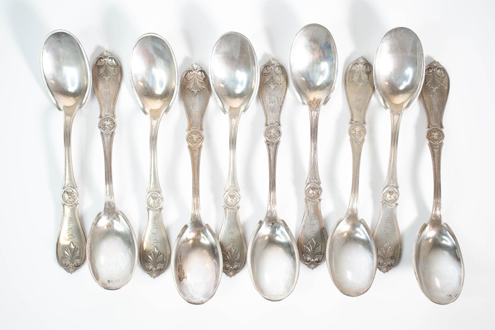Set of 10 Antique Coin Silver Spoons: Set of 10 Antique Coin Silver Spoons. Elegant set of ten antique coin silver spoons, each with a matching floral rosette motif and leaf finial design on the handle. Stamped 'COIN'. Likely dating from