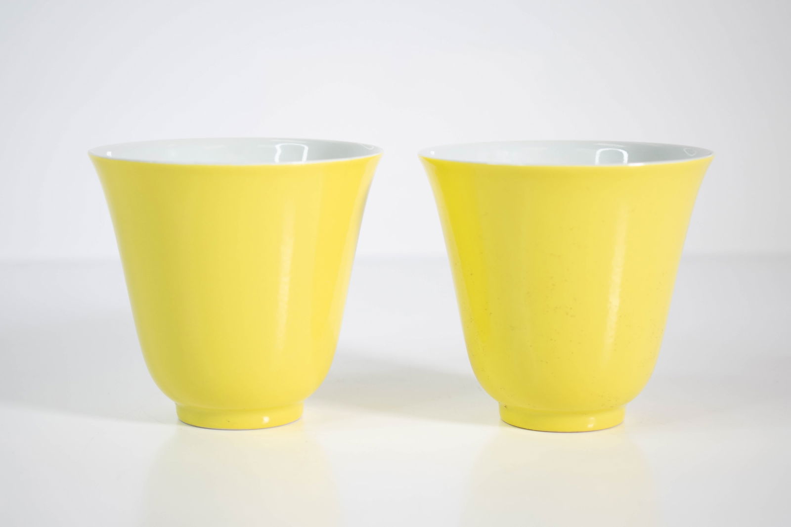 Chinese Small Lemon Yellow Cups: anice pair of cups with two concentric circles on thier bases each with a six character Yongzheng mark seal. Height 3" One cup has a visible hairline along the side.
