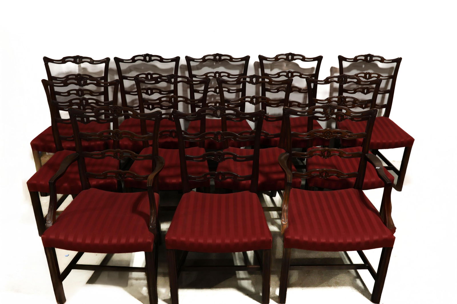Mahogany Chippendale Ladderback Chairs (12): A fine set of mahogany Chippendale ladderback chairs, crafted of solid mahogany. Chairs retain old old Sheraton striped upholstery. Each chair constructed with four ladder backs or splats. Stretcher b