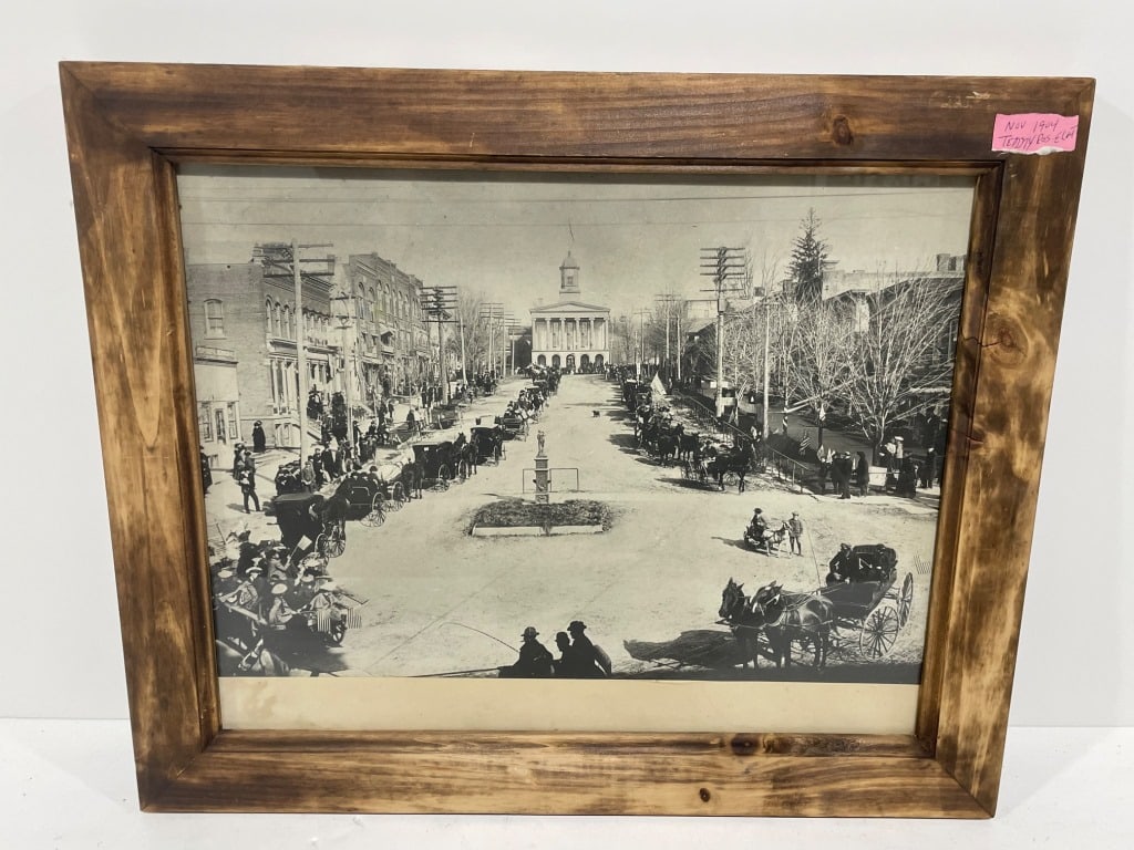Historic Teddy Roosevelt Photograph / Print 1904: Framed black-and-white photograph or print depicting a historic street scene with horse-drawn carriages, trees, and a building with a dome in the background. Housed in a rustic wood frame, the piece