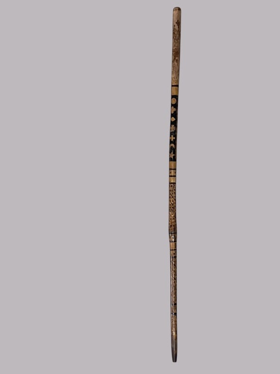 Carved Wood Walking Stick, 37 H: Carved wood walking stick featuring decorative geometric and symbolic patterns. The stick showcases hand-tooled designs along with black accents encircling the shaft. Measures 37 H. Suitable for decor
