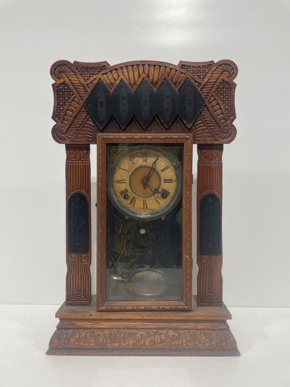 Antique Gingerbread Clock: Wood mantel clock featuring a carved design with decorative black accents and a glass front panel. The clock has Roman numeral markers on its face and stands approximately 14 inches wide by 23 inches
