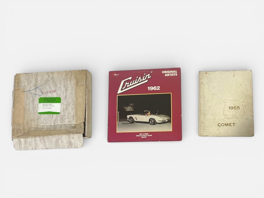 Cruisin' 1962 Vinyl Record and 1955 Yearbook: A Cruisin' 1962 vinyl record featuring original artists, with vibrant cover art of a vintage car. Includes a 1955 Comet yearbook with embossed cover design and interior illustrations. Largest piece