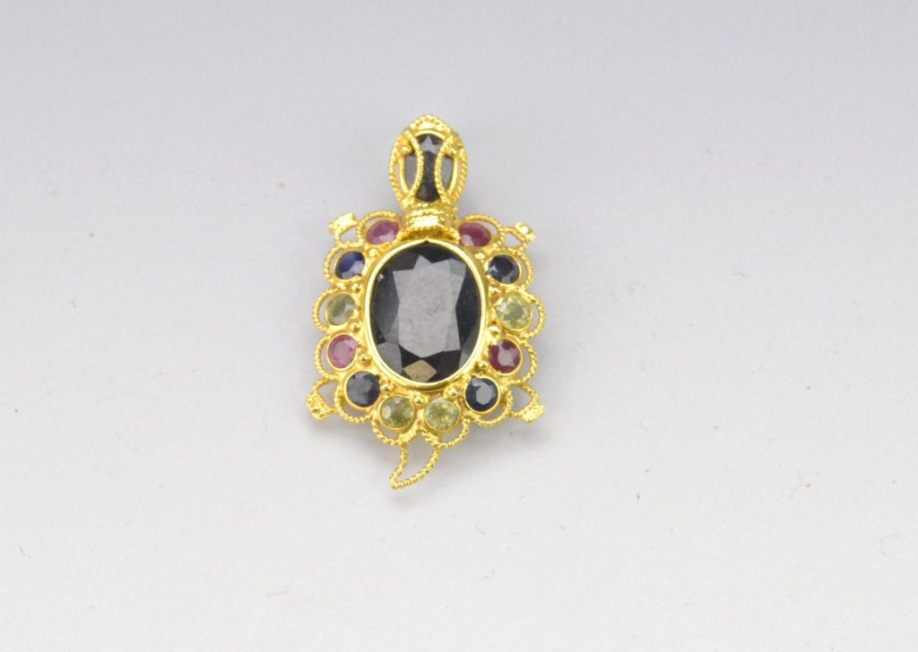 18k Multi-gem Turtle Pin-Pendant: Yellow gold Indonesian style tested 18K containing blue sapphires, rubies and peridot, shell is an approx. 10mm x 7mm oval blue sapphire, overall 18.5mm L. and weighs 1.0 dwt.