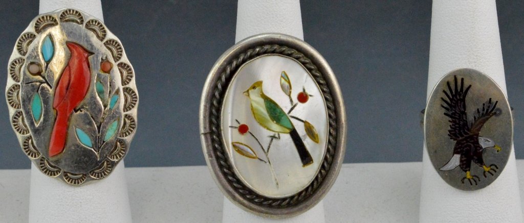 Zuni and Navajo Silver Inlay Ring Grouping: Includes (3) inlay rings, coral and turquoise inlay ring signed DB (Dean Brown) measures 1.5' size 6.25, mother of pearl and jet eagle ring measures 1" size 7.5, and large mother of pearl inlay songbi