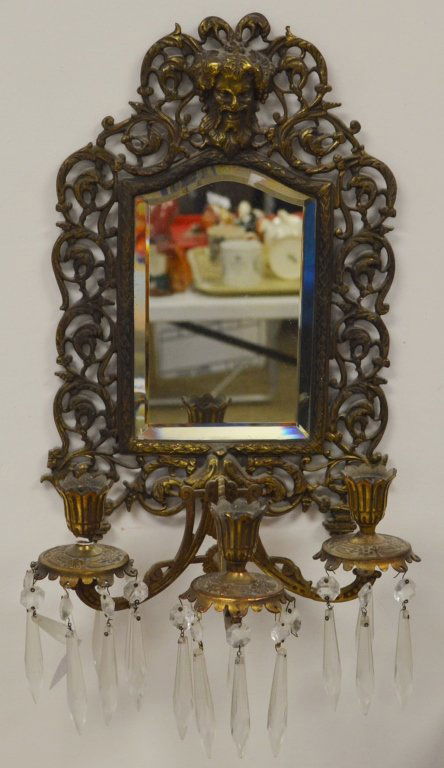 Brass Mirrored Wall Sconce with Beveled Glass: Unmarked. Ornate, with bearded God figure at top. Three candle holders with glass prisms. Measures 10.5" wide by 16.5" tall.
