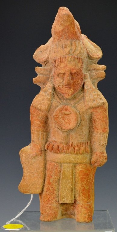 Mayan Mold-Made Figural Whistle, Jaina : Sotheby's: Late classic, c. 550-950 A.D. of a dignitary standing rigidly, with elaborate facial tattoos, wearing loin cloth, tasseled sash, elaborate headdress surmounted by a llama's (?) head, and with remains 