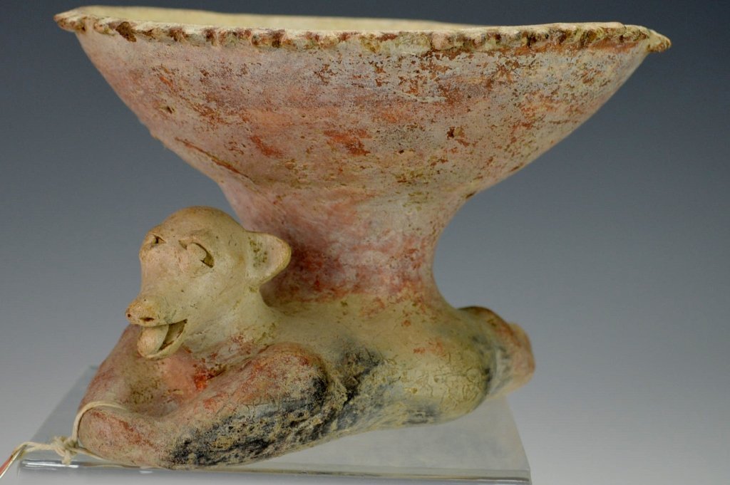 West Mexican Pottery Vessel : Sotheby's: Jalisco, Protoclassic c. 100 B.C. - A.D. 250, vessel with outward - flaring bowl and knopped border, the base molded in the form of the reclining stylized figure of a dog, with bared snout, lug ears, 
