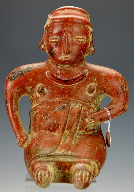 Colima Seated Female Figure : Sotheby's: Protoclassic, c. 100 B.C. - A.D. 250, the left hand placed to her pregnant stomach, wearing a gorget and banded headdress with two braids extended down her back, and painted overall in reddish - brown