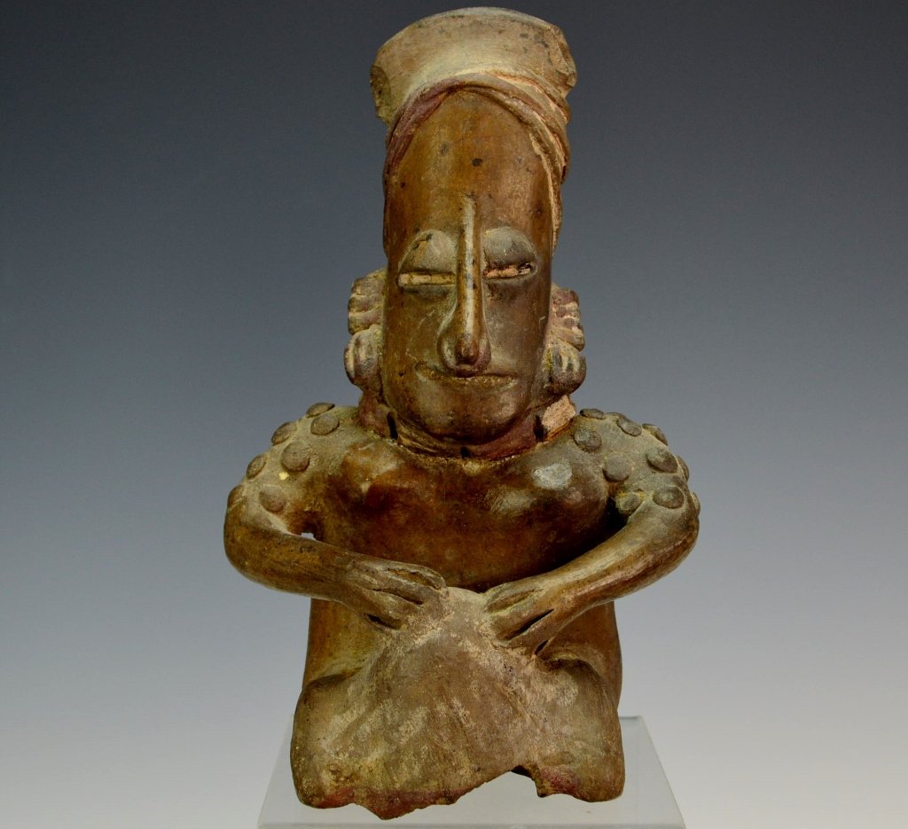 Jalisco Seated Figure Ameca Grey Type : Sotheby's: Protoclassic period, c. 100 B.C. - 250 A.D. Sitting in an occupational position with characteristic tassled earrings, applied ornamental shoulder decoration and crisscrossed headdress. Height 7.75". P