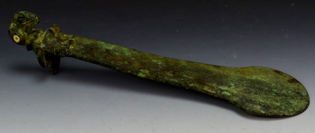 Peruvian Copper Knife (Tumi) : Sotheby's: Chimu, C. A.D. 1100-1400, knife with a crescentic blade, tapering haft , and surmounted by the figure of a bird, with large pierced beak, and inlaid shell eyes and crest. Length 6" Provenance: Sotheby