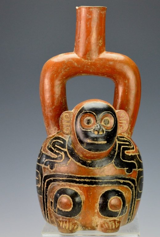 Late Chavin Stirrup Spout Vessel : Phillips: c. 700-400 B.C., molded with the protruding head of a monkey (repaired), incised glyph panel depicting aviary and feline motifs, reddish brown and black. Height 9.5" Provenance: Phillips 3/29/80 aucti