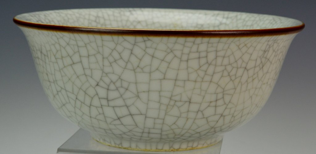 Chinese Guan Celadon Bowl: Gray crackled glaze exterior with gilt rim and has a raised footed base. Measures 4" x 9.5". A few small bubbles in the glaze of the rim, appear to have been caused in the firing process.