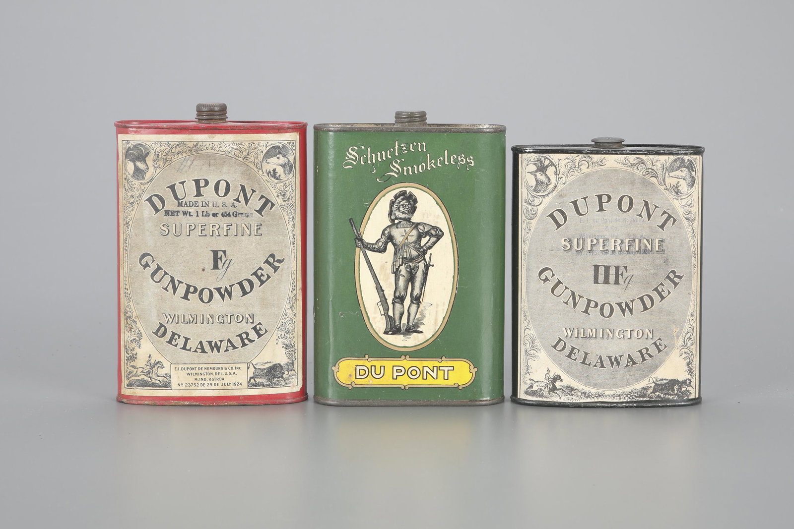 Three du Pont Powder Tins: Three du Pont Powder Tins largest is 6 1/4 in. Three oval tins with three different labels. The black tin has a "Du Pont HF Superfine Gunpowder" label with four corner vignettes: stag head, dog head, 