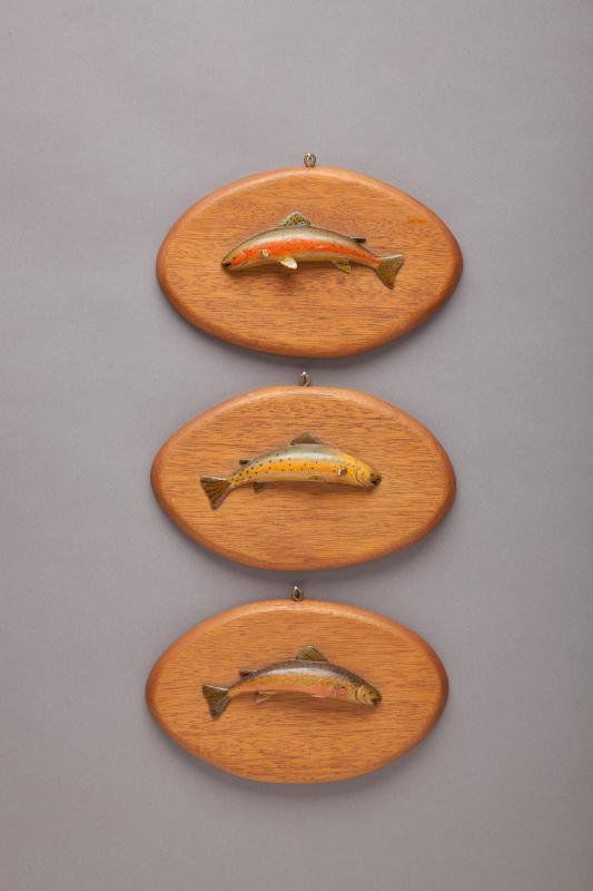 Three Miniature Trout Plaques: Three Miniature Trout Plaques Roberts, c. 1950 Original paint with missing pelvic and pectoral fins. Five-inch-long cut-throat, brook, and rainbow trout carvings mounted on oval mahogany plaques measu