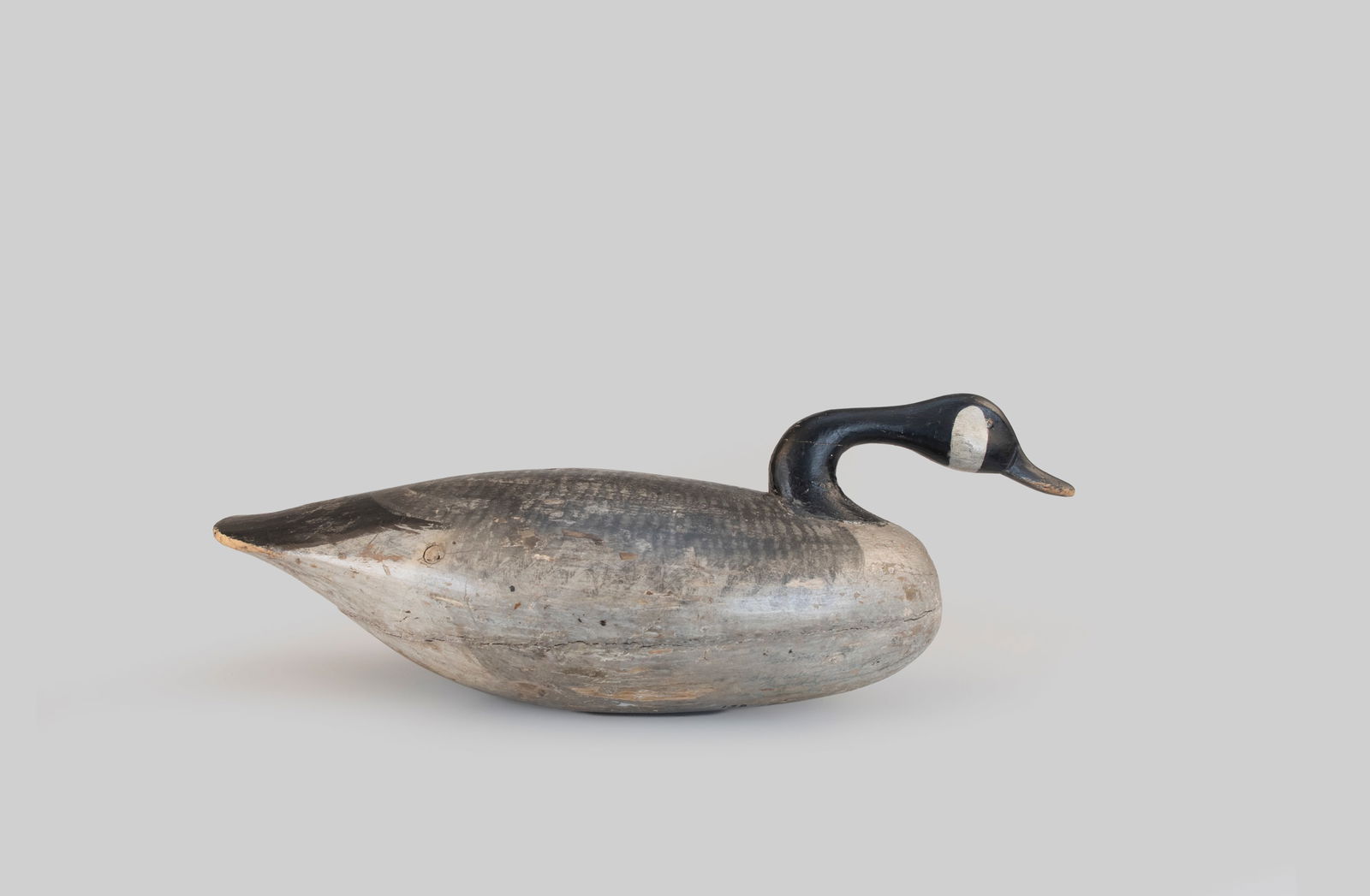 Canada Goose by Ira D. Hudson (1873-1949): Canada Goose Ira D. Hudson (1873-1949) Chincoteague, VA, c. 1920 25 1/2 in. long The underside of this snaky-head carving has William J. Mackey's inked inscription that reads "Canada Goose Bay side