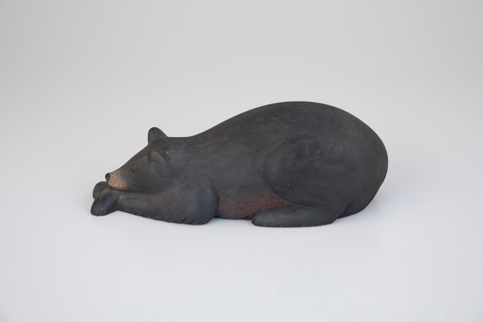 Resting Black Bear by Marty Collins (b. 1960): Resting Black Bear Marty Collins (b. 1960) East Wareham, MA 11 in. long Signed with the maker's rectangular ink stamp on the bottom. Original paint with light wear. Provenance: Mike Caton Collection