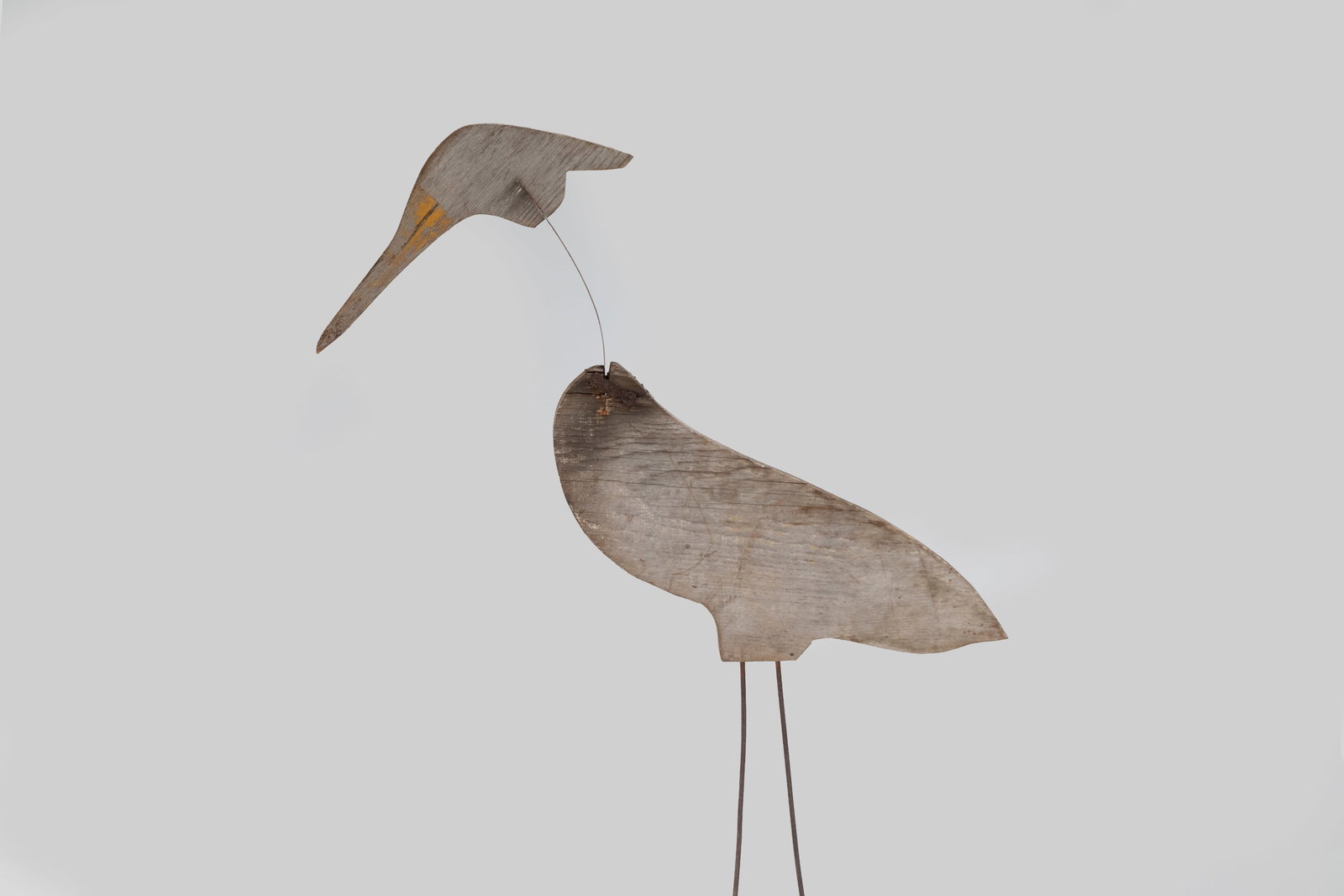 Heron: Heron 39 1/2 in. tall A life-size heron carving with wire legs and a flat metal neck. The head bounces back on its flexible metal neck, likely designed to move in the wind. It is constructed from a 3/