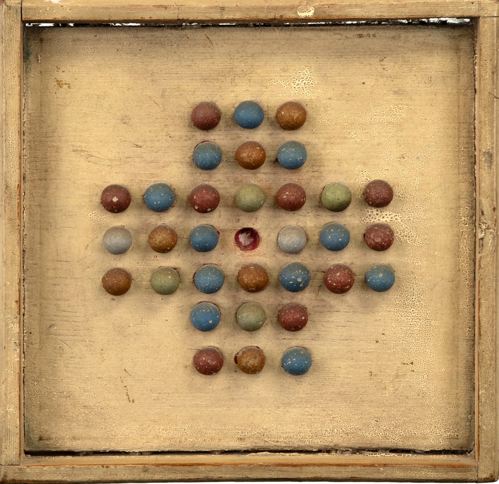 Solitaire Marble Gameboard: Solitaire Marble Gameboard 10 by 10 in. A Solitaire marble gameboard, complete with a set of what appears to be its original clay marbles set against a cream background with a great old craquelured