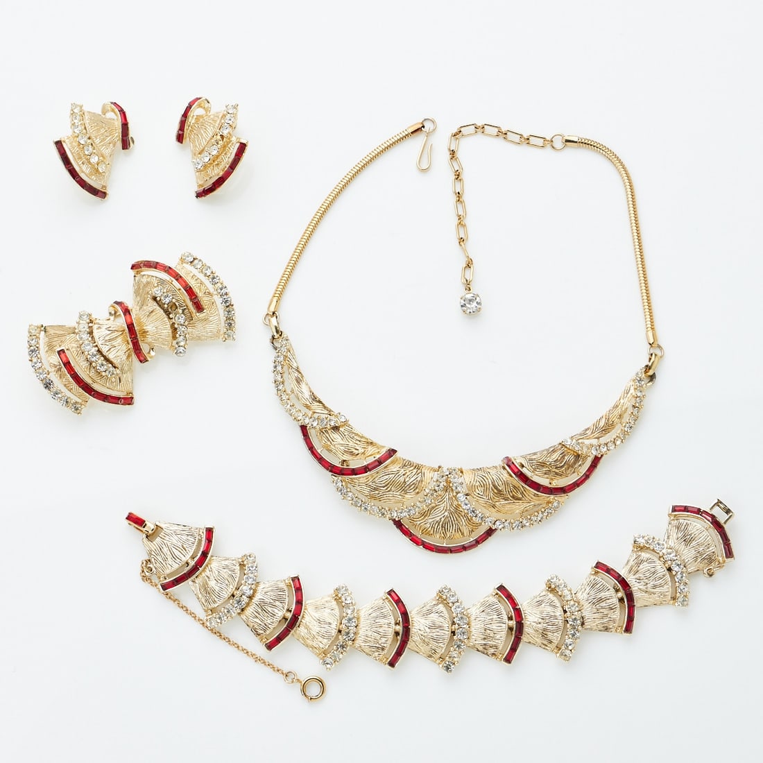 CORO - Vintage - Schmuckset mit Straß: CORO - Vintage - Schmuckset mit StraßCollier, Armband, Brosche und Paar Ohrclips (4 Teile) Coro Jewelry, Cohn & Rosenberger, New York, USA. Ca. 1950 - 1960er Jahre. Metall, vergoldet. Roter und w