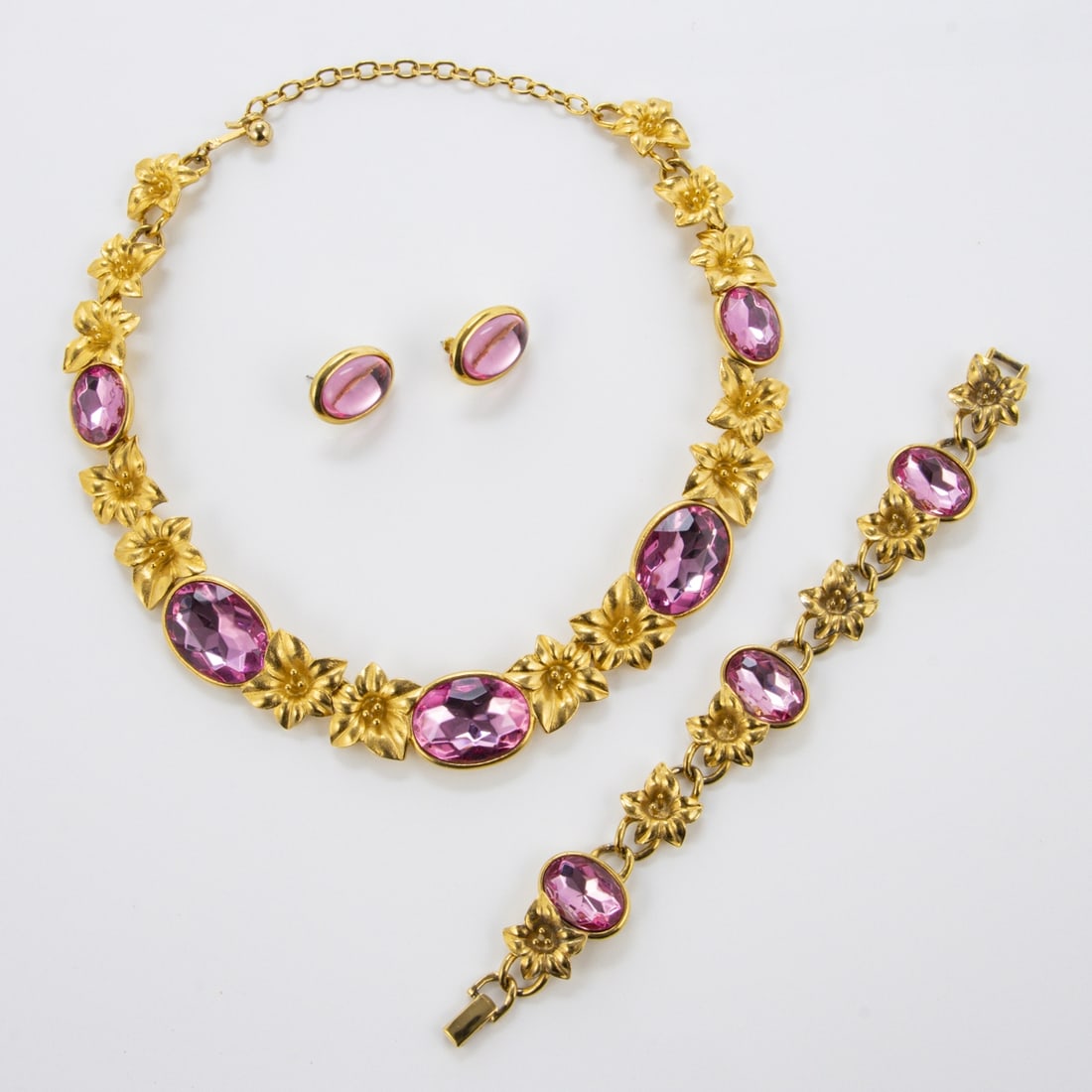 TRIFARI Kunio Matsumoto - Pink Kristalle Schmuckset (3 Teile): TRIFARI Kunio Matsumoto - Pink Kristalle Schmuckset (3 Teile)New York, um 1970. Collier, Armband und Paar Ohrclips. Metall, goldfarben mit pinken Kristallen. Designer: Kunio Matsumoto. Sign.: TRIFARI