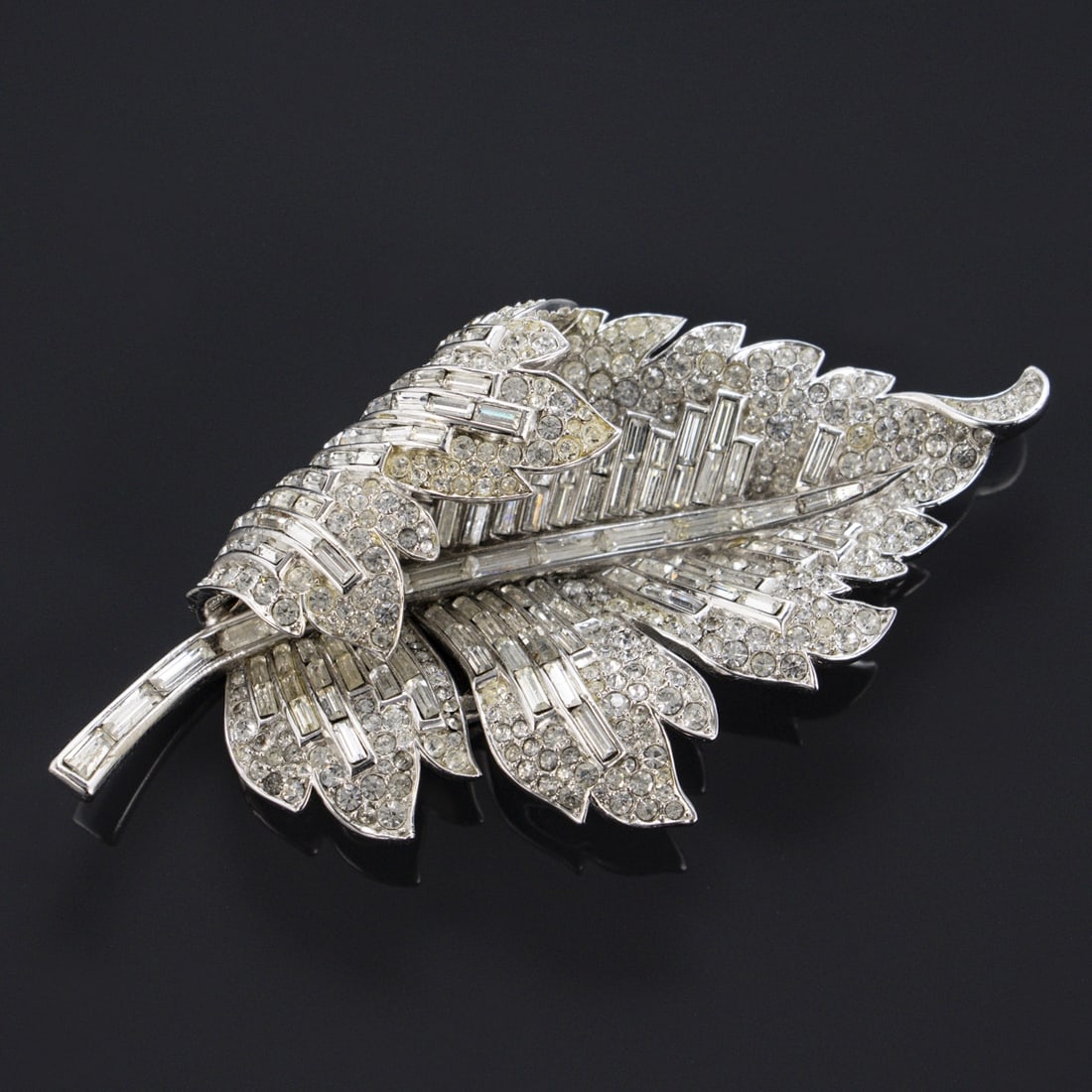 TRIFARI Alfred Philippe - Vintage blattfoermige Strass-Brosche: TRIFARI Alfred Philippe - Vintage blattfoermige Strass-BroscheNew York, um 1940. Metall, silberfarben mit Strass, blattfoermig, signiert: TRIFARI mit Krone ueber dem "T". Brosche Masse: 10 x 5 cm. Seh