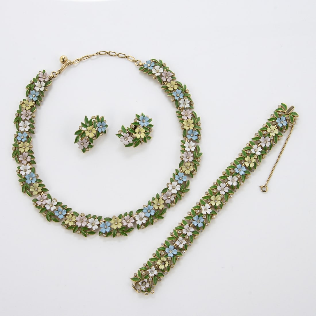 TRIFARI Alfred Philippe - Vintage Bluemchen Emaille-Schmuckset (3 Teile): TRIFARI Alfred Philippe - Vintage Bluemchen Emaille-Schmuckset (3 Teile)New York, um 1950 - 1970. Collier, Armband und Paar Ohrclips. Metall, goldfarben, Strass, Emaille. Collier-D. 13 cm. B. ca. 1,8