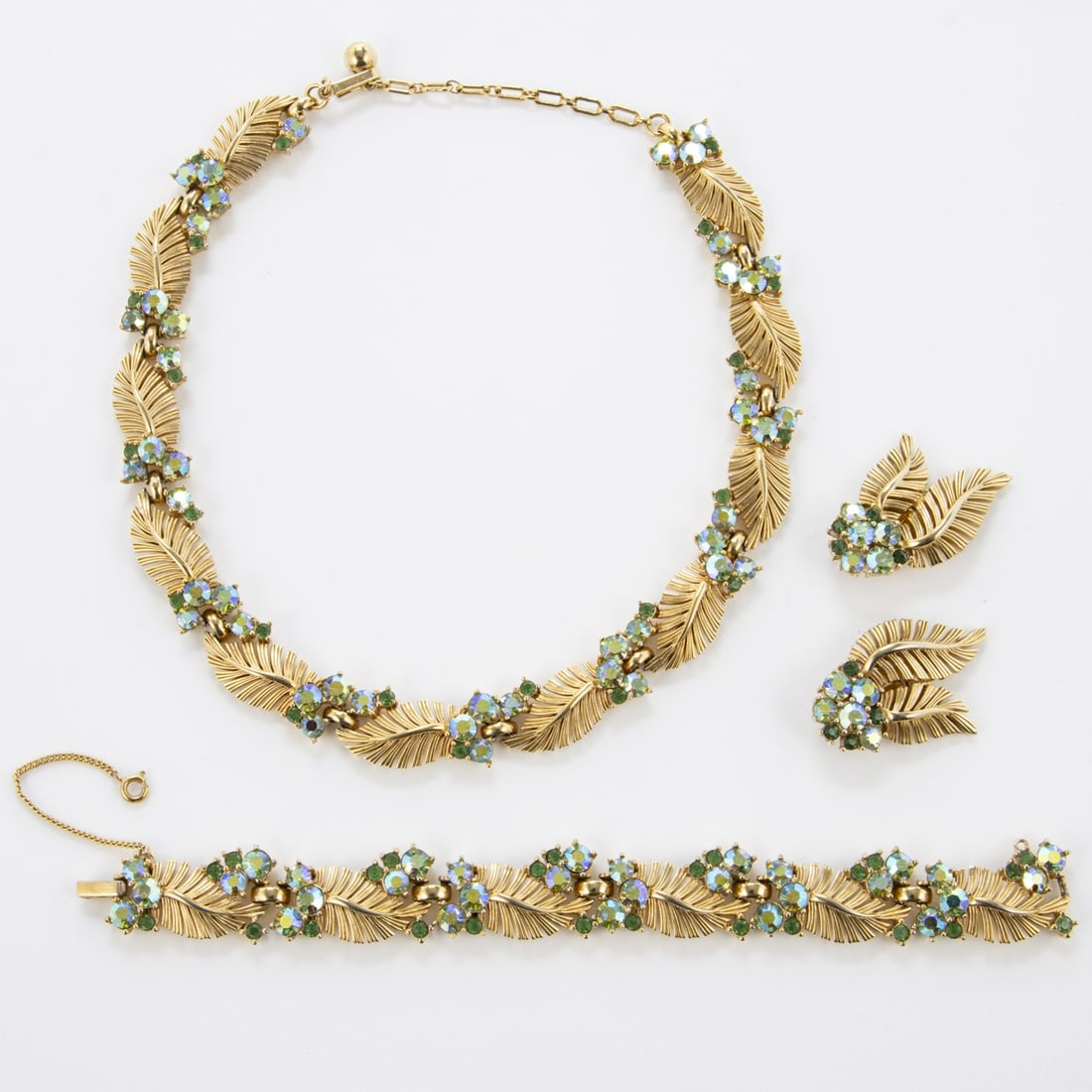 TRIFARI Alfred Philippe - Vintage-Schmuckset mit blauen und gruenen Strasssteinen und goldenen: TRIFARI Alfred Philippe - Vintage-Schmuckset mit blauen und gruenen Strasssteinen undgoldenen Blaettern (3 Teile) New York, 1950. Collier, Armband und Paar Ohrclips. Metall, vergoldet mit Strass. Coll