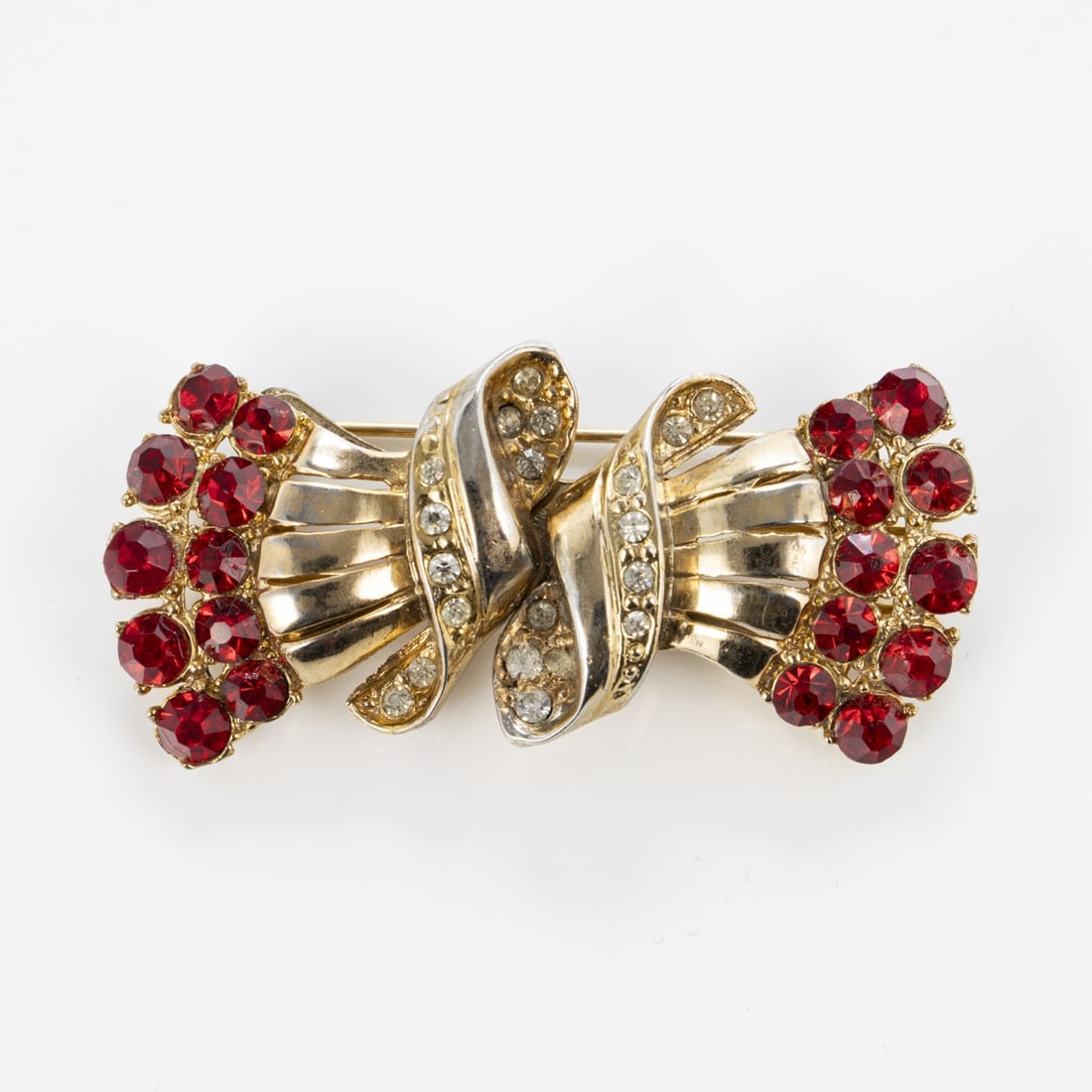 Coro Duette - Vintage Schleifen-Brosche mit Halter: Coro Duette - Vintage Schleifen-Brosche mit HalterCoro Cohn & Rosenberger Jewelry, New York, USA. Ca. 1960er Jahre. Metall, goldfarben, Faux-Rubine, Strass. Nadel mit Sicherheitsschieber. Masse: 5,8 x