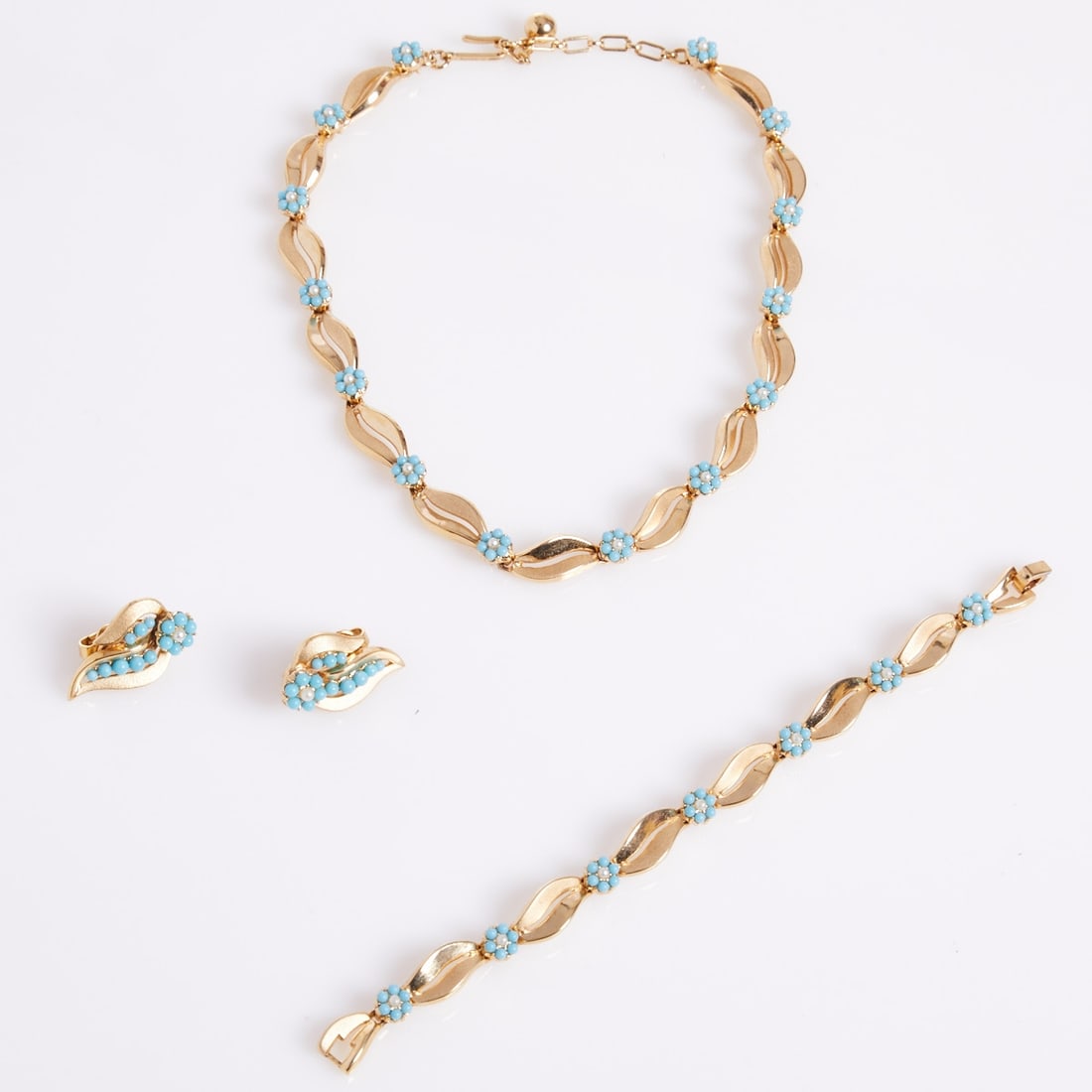 TRIFARI Alfred Philippe - Vintage Parure with Floral and Bow Motif (3 pieces): TRIFARI Alfred Philippe - Vintage Parure with Floral and Bow Motif (3 pieces) Necklace, bracelet, and pair of ear clips. Crown Trifari, New York, circa 1960. Metal, gold-colored and likely gold-plated