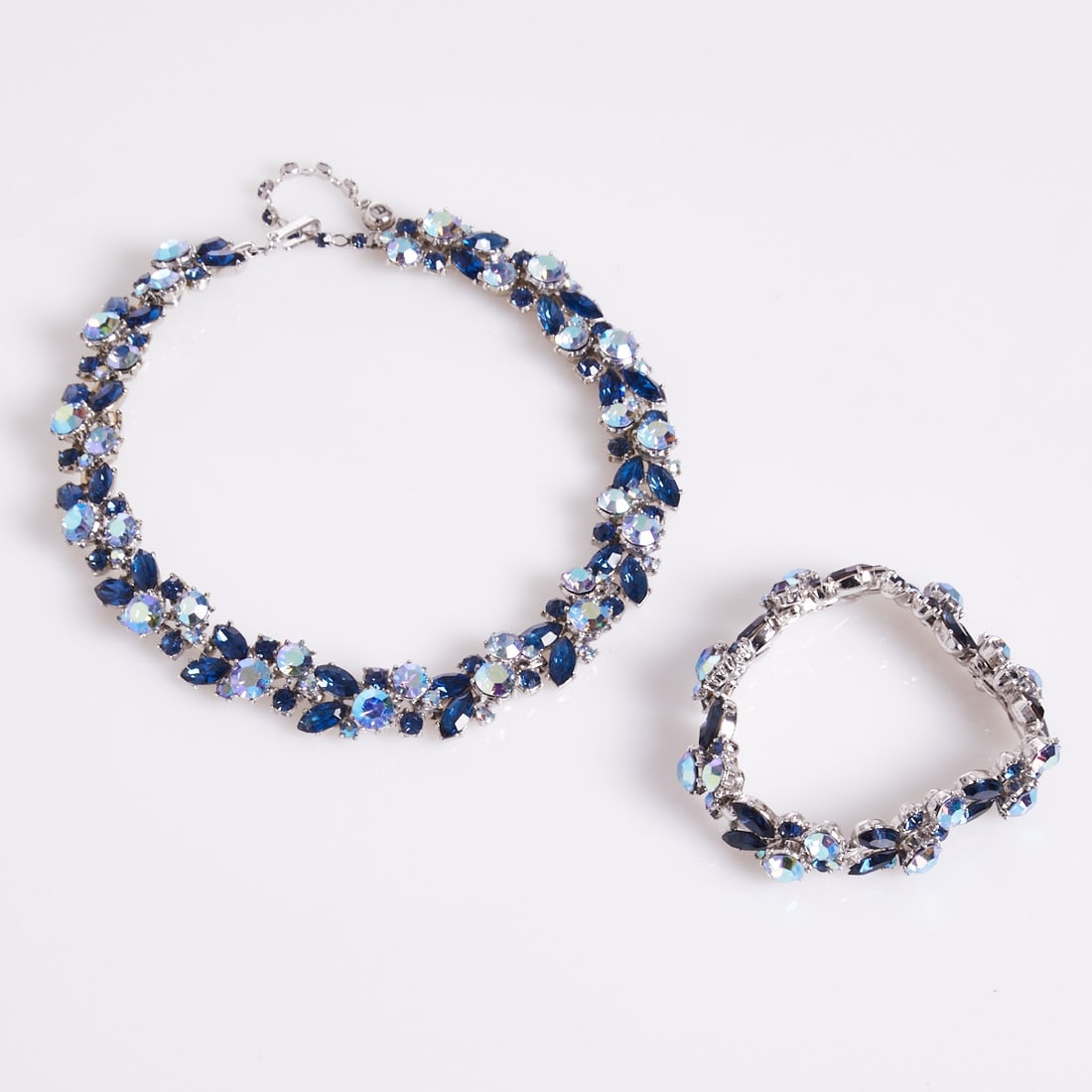 TRIFARI - Vintage Necklace and Bracelet with Blue Rhinestones: TRIFARI - Vintage Necklace and Bracelet with Blue Rhinestones Trifari, New York, c. 1950. Metal, silver-colored, with blue rhinestones and Aurora Borealis rhinestones. Weight: 122 g. Necklace L. 35-40