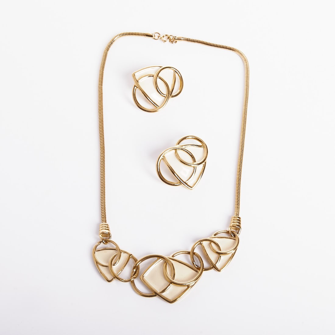 TRIFARI Kunio Matsumoto - Abstract Necklace in Gold Color and Matching Pair of Clip Earrings: TRIFARI Kunio Matsumoto - Abstract Necklace in Gold Color and Matching Pair of Clip Earrings Trifari, New York, c. 1970. Metal, gold-colored with enamel. Necklace L. 50 cm. W. approx. 3.5 cm. Clip ear