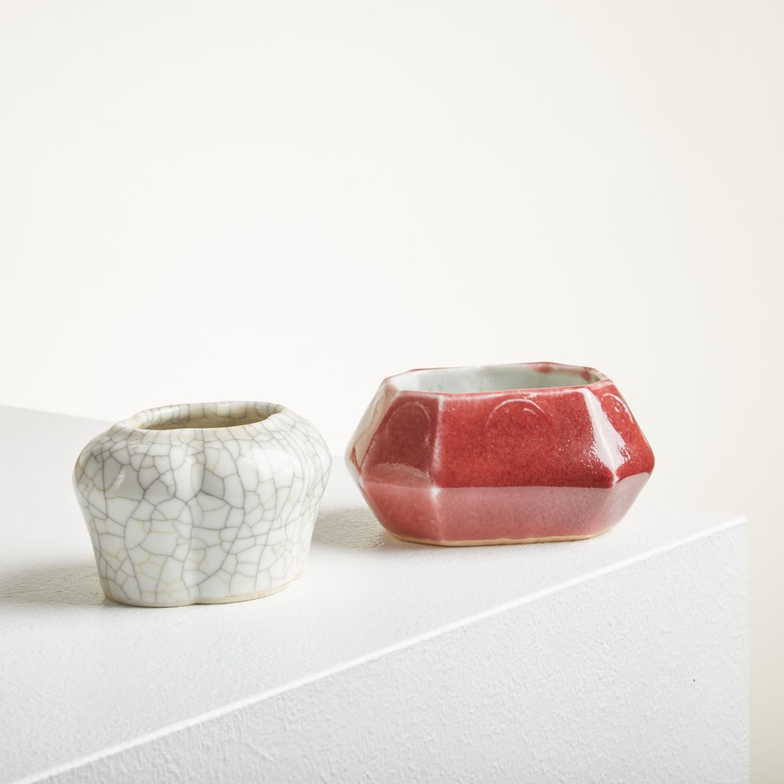 2 small water pots for brushes: Two small water pots for brushes China, 19th / 20th century. Red pot: Porcelain, polychrome painted red on glaze. Octagonal, each side embossed with a round Chinese motif underglaze. H. 4.8 cm. D. of