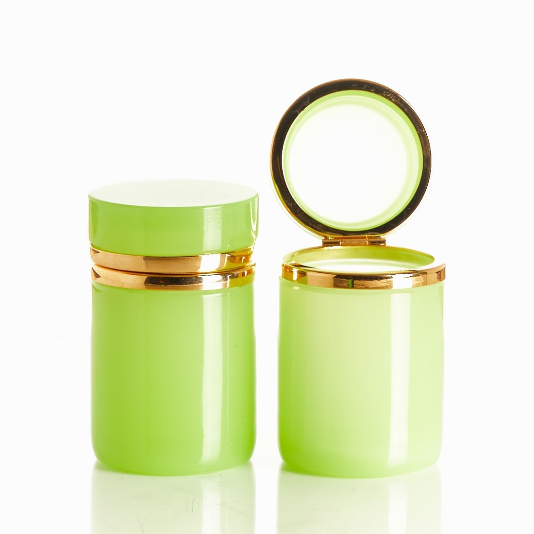 Pair of round covered boxes, uranium glass - Art Deco. France, circa 1935-1940.: Pair of round covered boxes - Art Deco France, circa 1935-1940. Uranium glass: Thick-walled, light green opal glass, ground and polished. Brass mounting with hinge. H. 9.5 cm, D. 6 cm.