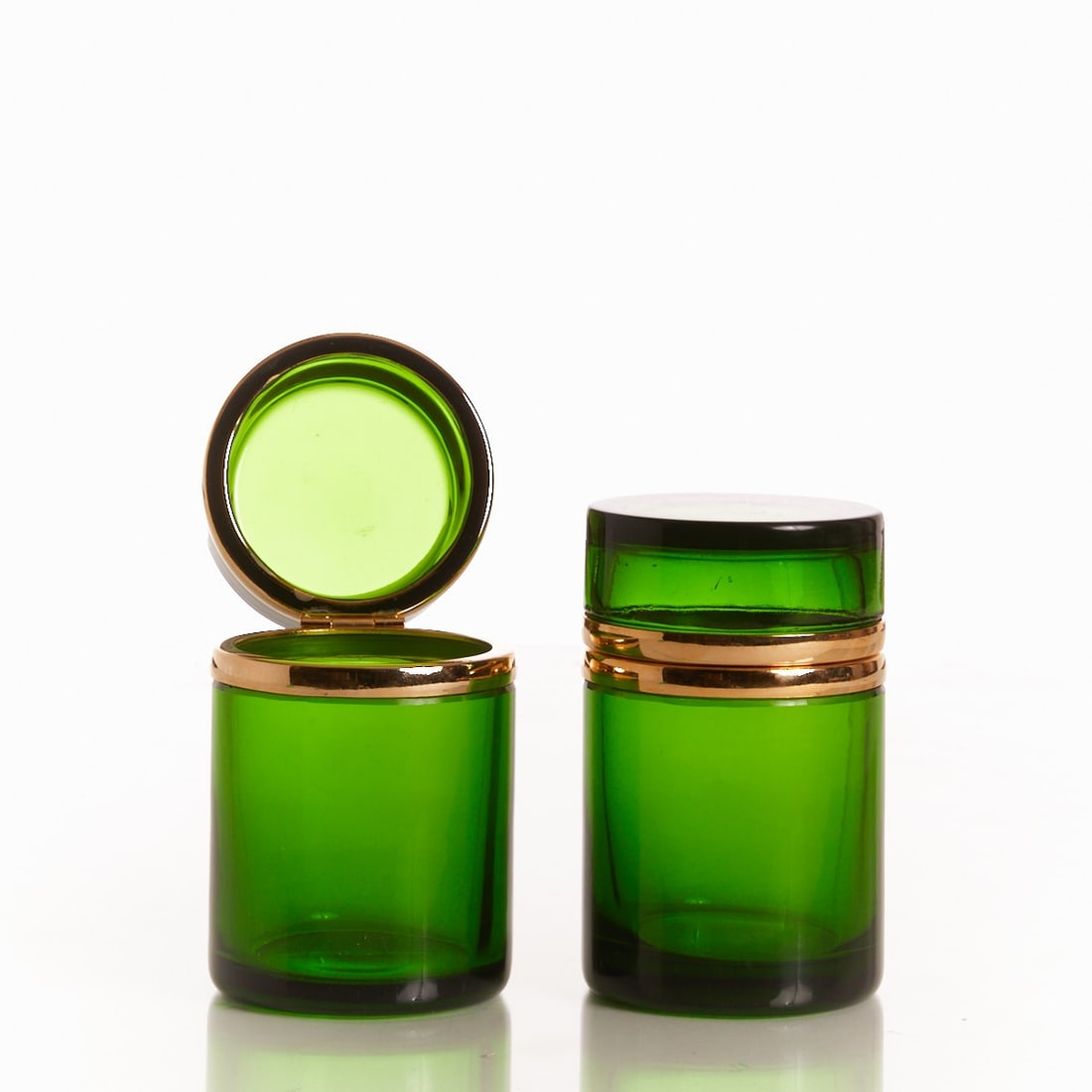 Pair of round lidded boxes - Art Déco. France, circa 1935-1940.: Pair of round lidded boxes - Art Déco France, circa 1935-1940. Thick-walled, dark green glass, cut and polished. Brass mounting with hinge. H. 10 cm, D. 6 cm.