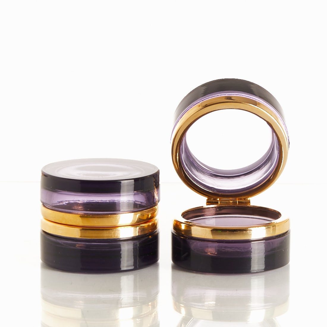 Pair of round lidded boxes - Art Deco.: Pair of round lidded boxes - Art Deco France, circa 1935-1940. Thick-walled, violet glass, cut and polished. Brass mounting with hinge. H. 4.5 cm, D. 6 cm. - Condition: a minimal chip on the lower lid