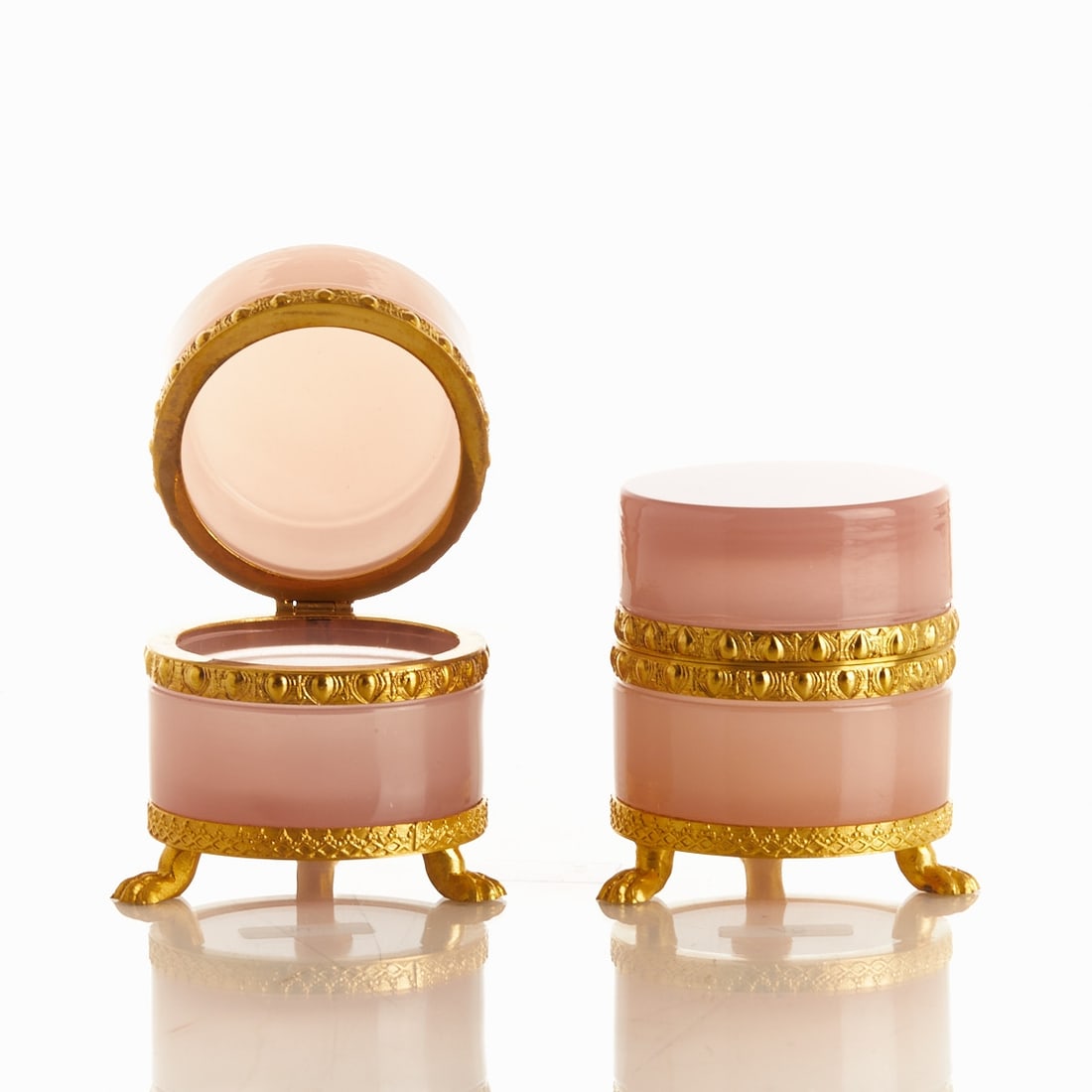 Pair of round lidded boxes on mounting with lion's feet - Art Deco. France, circa 1935-1940.: Pair of round lidded boxes on mounting with lion's feet - Art Deco France, circa 1935-1940. Thick-walled, pink opal glass, slightly translucent, cut and polished. Embossed brass mounting with hinge. E