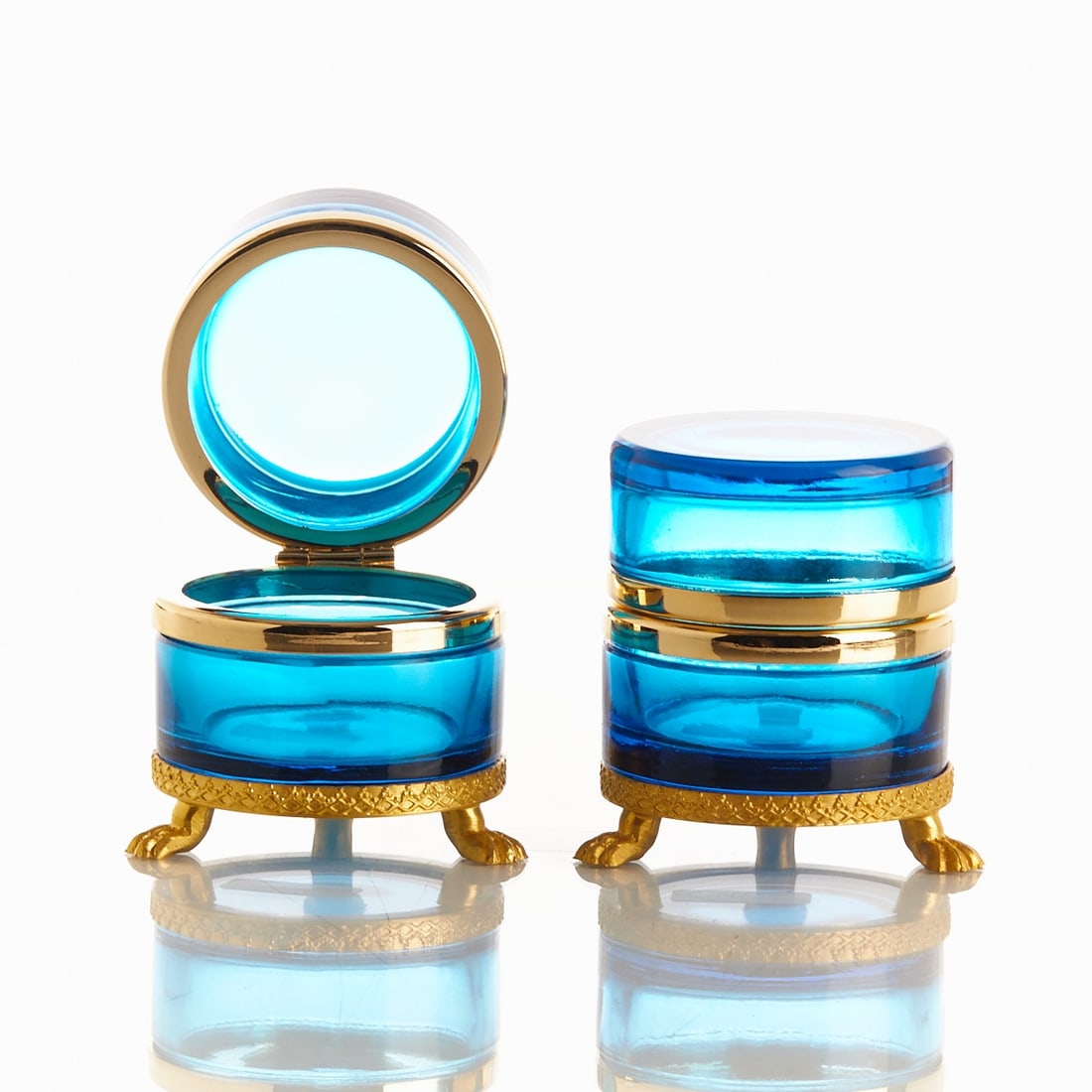 Pair of round lidded boxes on mounting with lion's feet - Art Déco. France, circa 1935-1940.: Pair of round lidded boxes on mounting with lion's feet - Art Déco France, circa 1935-1940. Thick-walled, blue glass, cut and polished. Brass mounting with hinge. Embossed mounting with lion's feet.