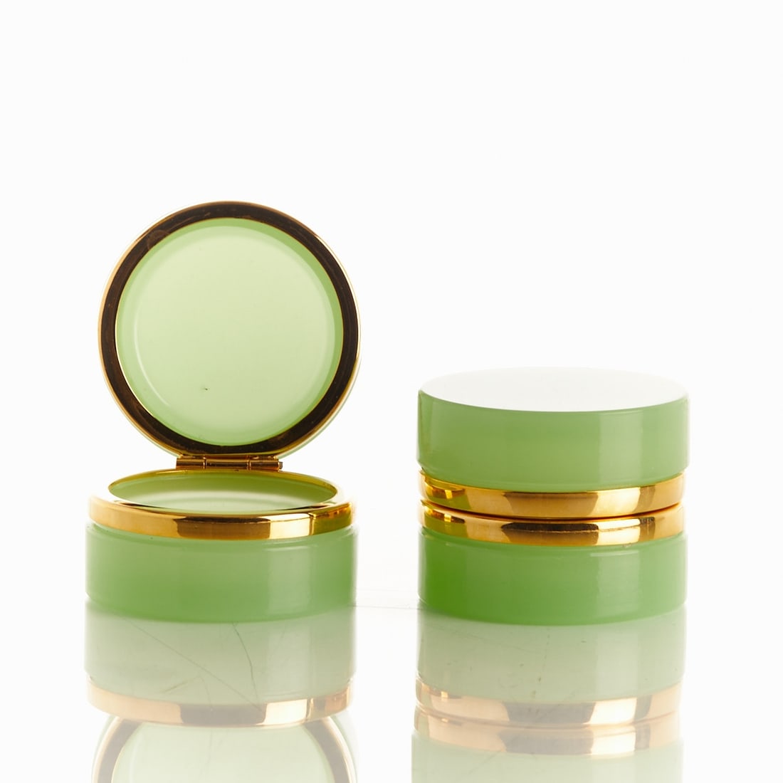 Pair of round lidded boxes - Art Déco. France, circa 1935-1940.: Pair of round lidded boxes - Art Deco France, circa 1935-1940. Thick-walled, light green opal glass, cut and polished. Brass mounting with hinge. H. 4.5 cm, D. 6 cm.