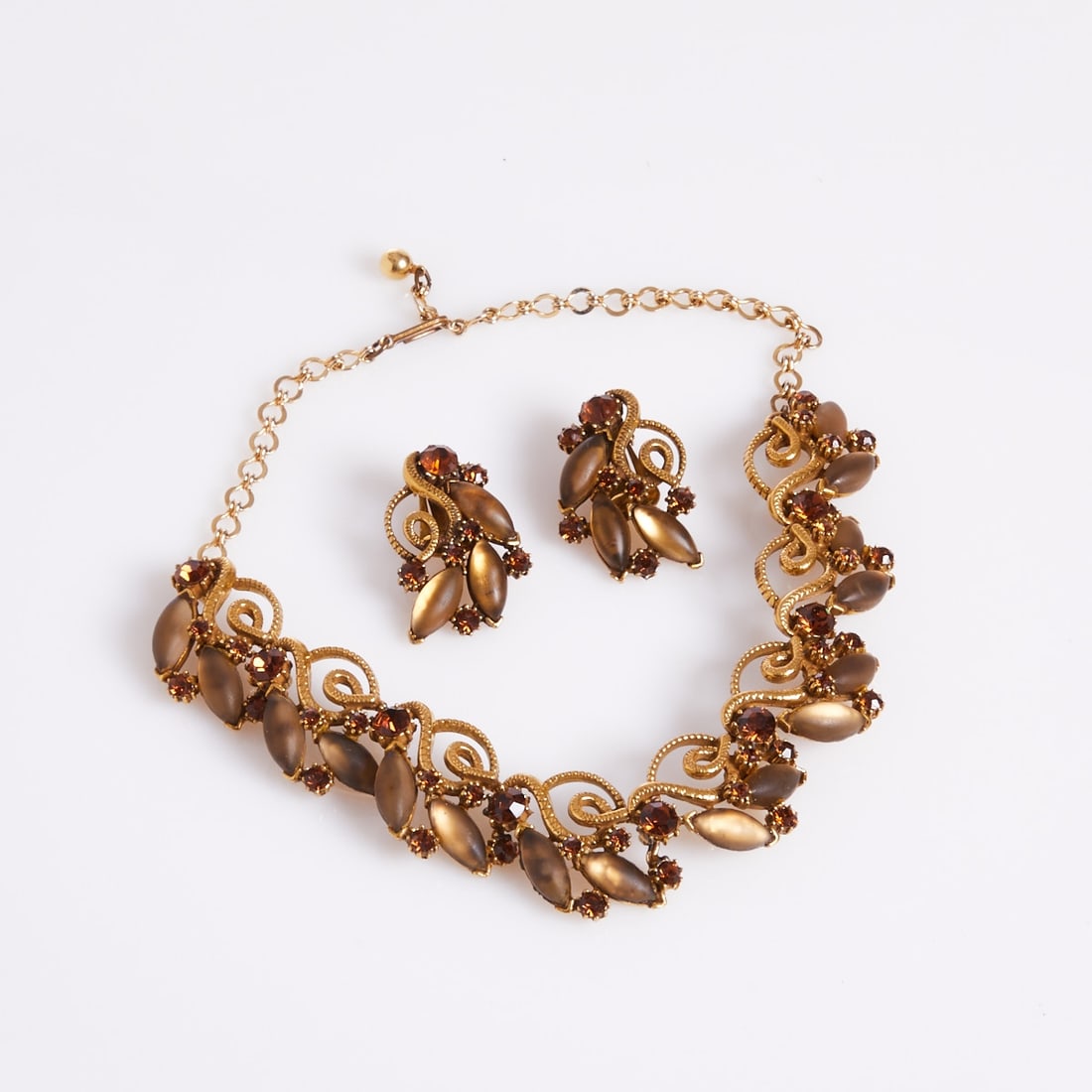 FLORENZA - Vintage Necklace and Pair of Ear Clips: FLORENZA - Vintage Necklace and Pair of Ear Clips Florenza Co., New York, USA, approx. 1960s. Gold-colored metal. Rhinestones. Oval-cut glass cabochons. Total weight: 77 g. Necklace L. max. 40 cm. W.