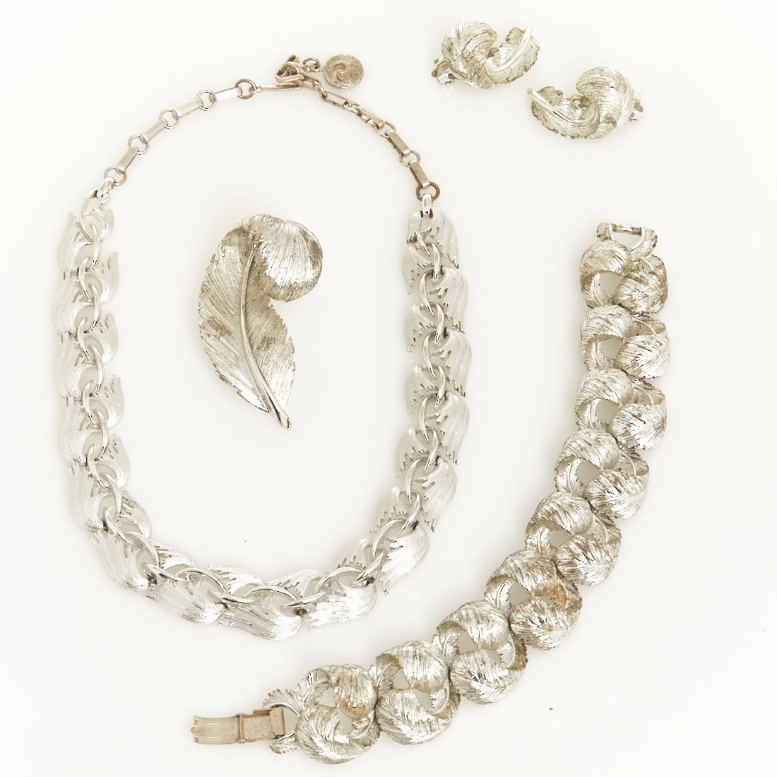 LISNER - Vintage Silver-Colored Jewelry Set with Feather Motif (4 pieces): LISNER - Vintage Silver-Colored Jewelry Set with Feather Motif (4 pieces) Necklace, bracelet, brooch, and pair of ear clips. Lisner, New York, USA. approx. 1960. Metal, silver-colored. Weight: 160 g.