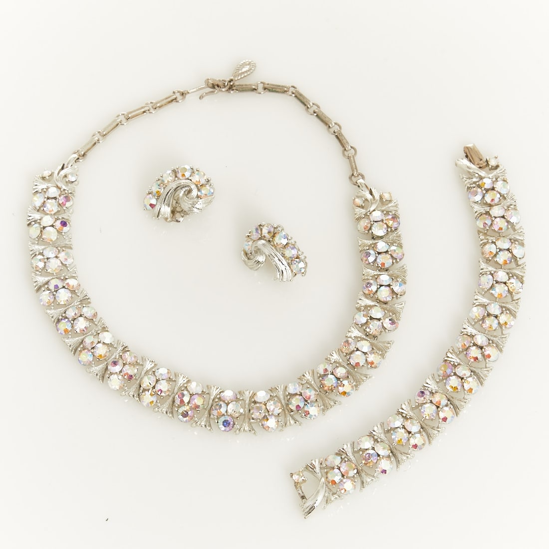 LISNER - Vintage Statement Jewelry Set with Aurora Borealis Rhinestones (3 Pieces): LISNER - Vintage Statement Jewelry Set with Aurora Borealis Rhinestones (3 Pieces) Necklace, bracelet, and pair of ear clips. Lisner, New York, USA. Approx. 1960. Metal, white gold-colored. Aurora Bor