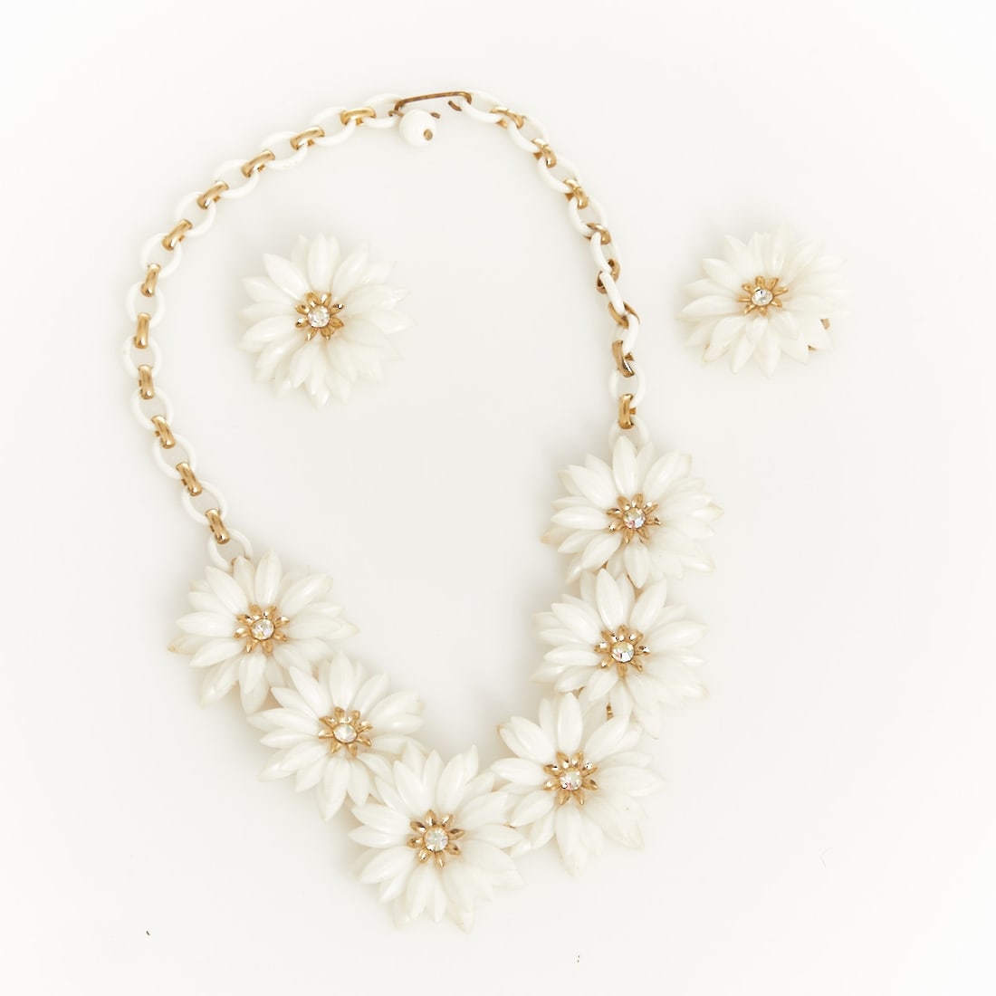 CORO - Vintage Necklace and Pair of ''Daisy'' Ear Clips: CORO - Vintage necklace and pair of ''Daisy'' ear clips Coro (Cohn & Rosenberger Jewelry), New York, USA, circa 1940s. Metal, gold-coloured; rhinestones; plastic. Weight: 29 g. Necklace L. 30 - 45