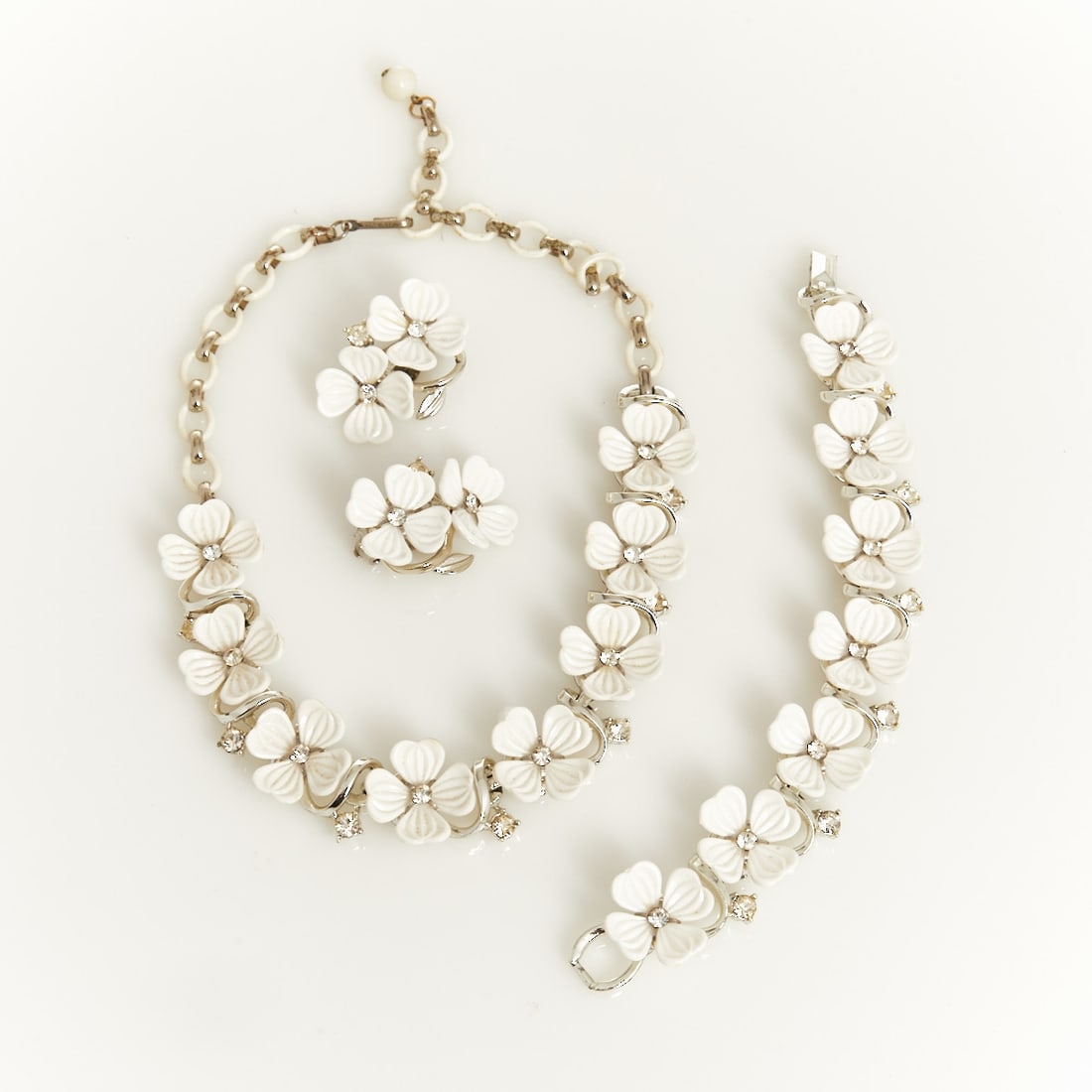 LISNER - Vintage Parure with White Flowers (3 pieces): LISNER - Vintage Parure with White Flowers (3 pieces) Necklace, bracelet, and pair of ear clips. Lisner, New York, circa 1950. Metal, silver-colored; crystal rhinestones; Lucite. Total weight: 77 g. N